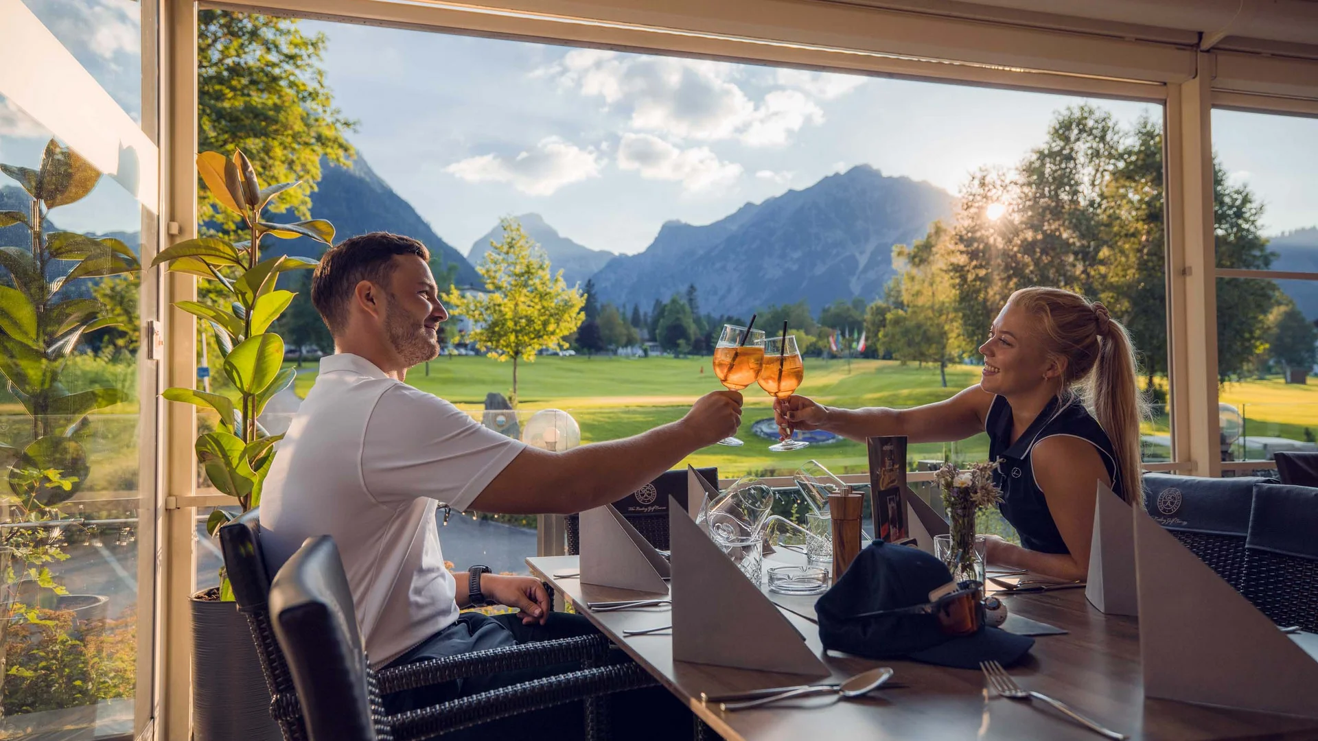 Euer Golfhotel am Achensee Paar stößt mit Getränken in einem Restaurant mit Bergblick an