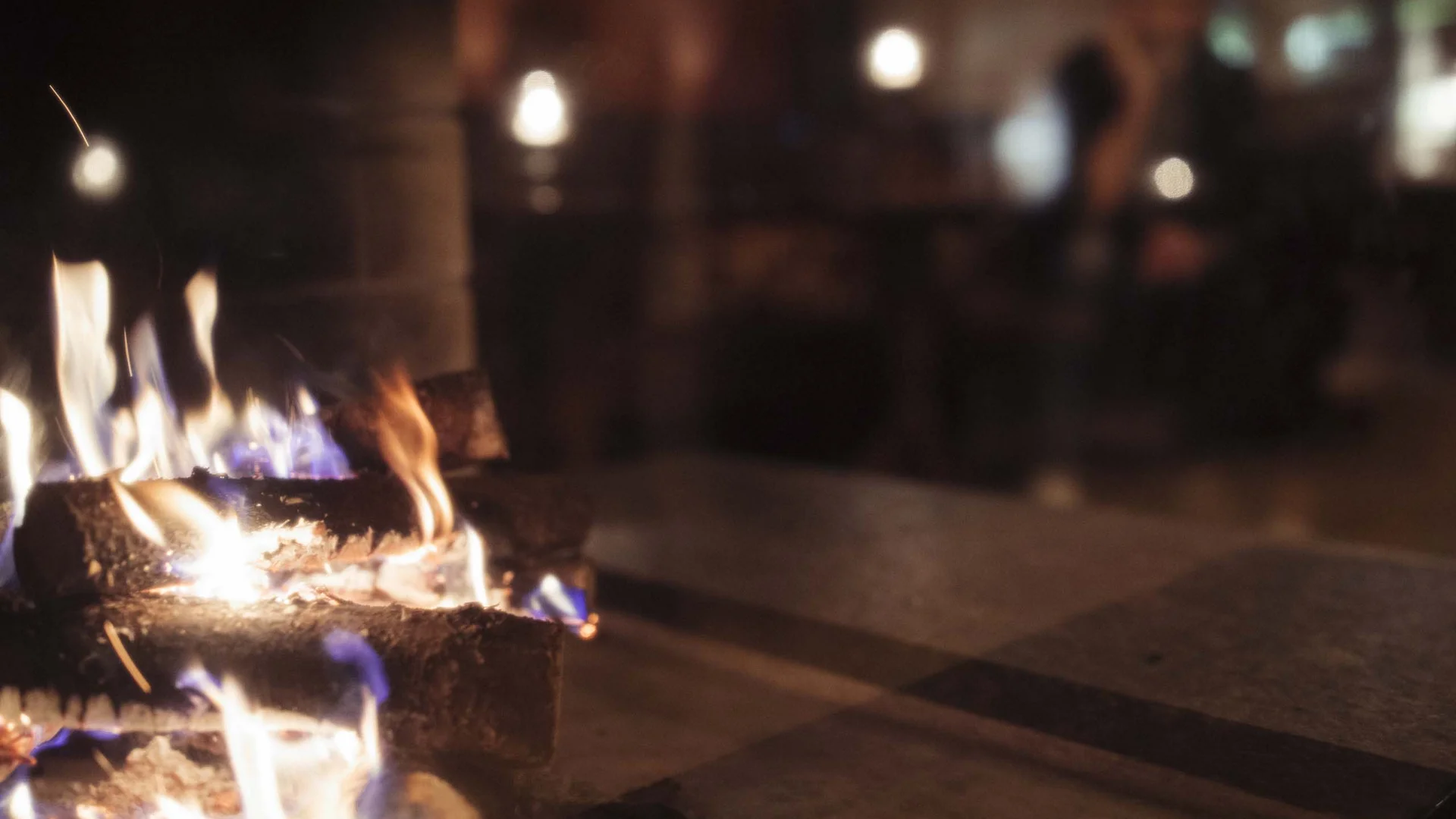 Auf in ein romantisches Hotel in Tirol Nahaufnahme eines Feuers mit brennenden Holzscheiten drinnen, verschwommener Hintergrund