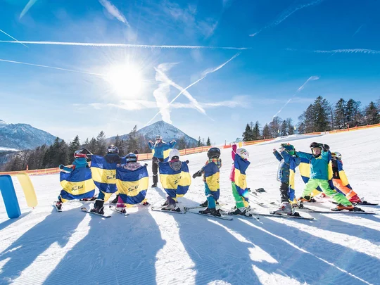 Euer Familienhotel am Achensee Kinder beim Skikurs mit Ausbilder auf sonniger Piste vor Bergkulisse