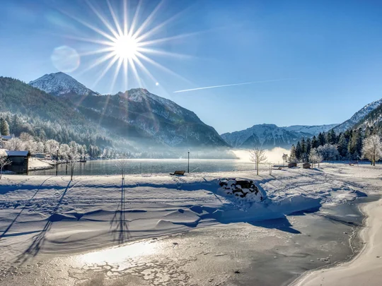 In, auf und rund um den Achensee Verschneite Landschaft mit Bergen, gefrorenem See und strahlender Wintersonne