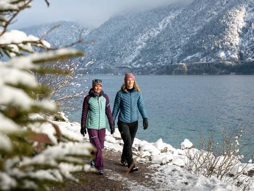 Wanderhotel Tirol: durchs Karwendel wandern und biken Zwei Frauen wandern im Winter am verschneiten Seeufer mit Bergen im Hintergrund