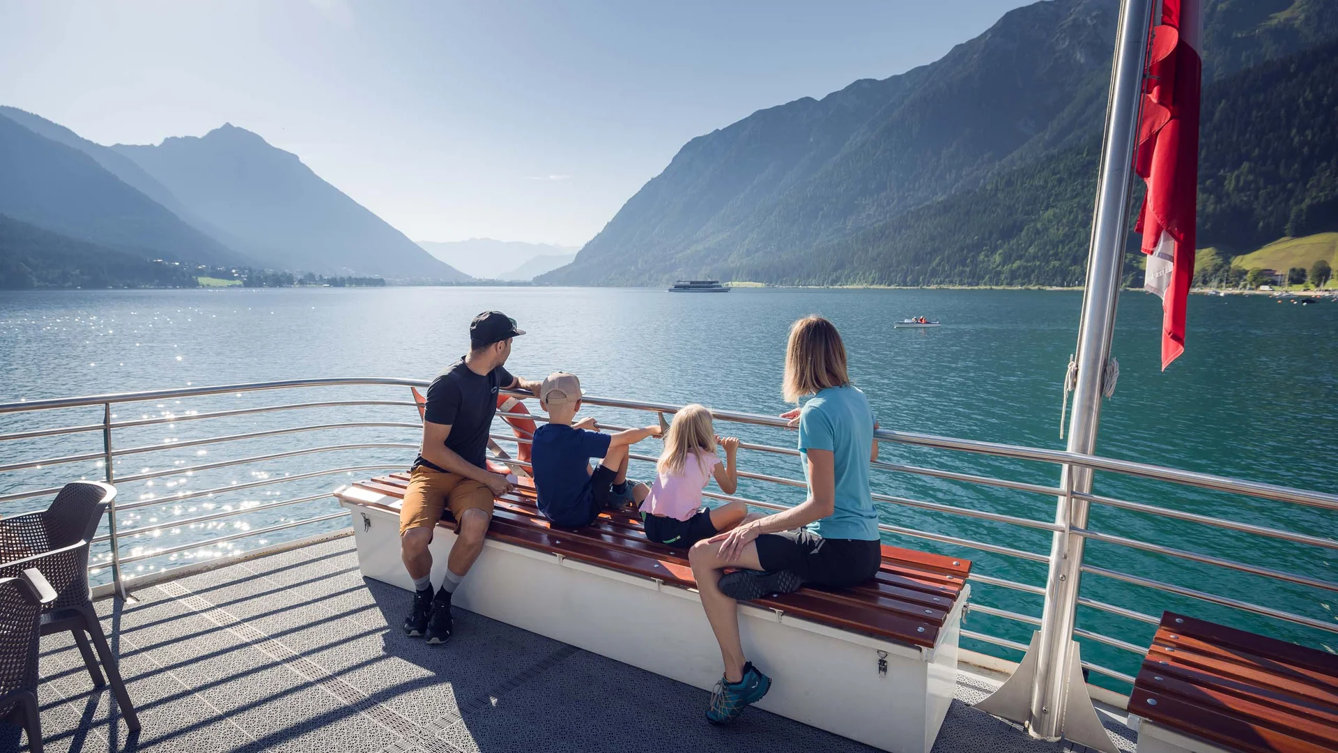 Euer Familienhotel am Achensee Familie genießt Bootsfahrt auf See mit Bergsicht an sonnigem Tag