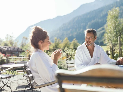 Auf in ein romantisches Hotel in Tirol Paar in Bademänteln genießt Kaffee im Freien mit Bergblick