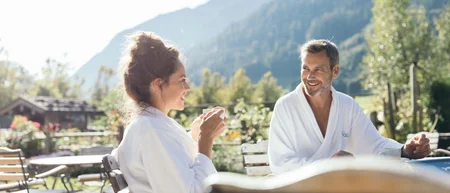 Paar in Bademänteln genießt Kaffee im Freien mit Bergblick