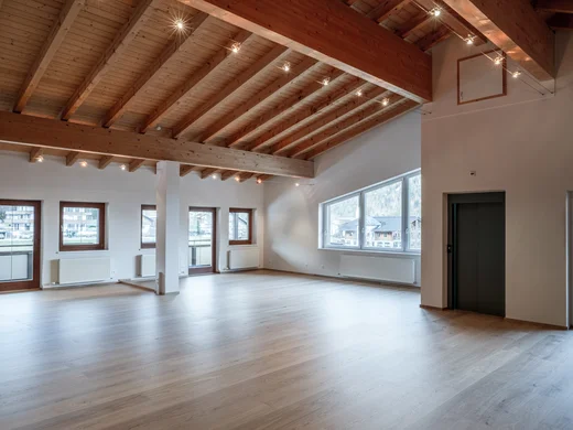 Leerer heller Raum mit Holzbalkendecke und mehreren Fenstern