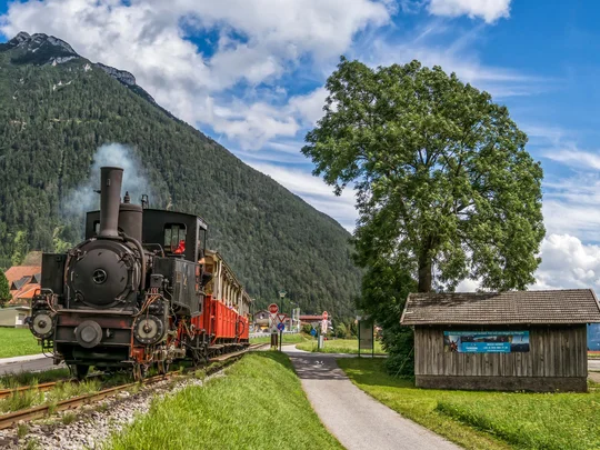 Sehenswürdigkeiten am Achensee rund um den Wiesenhof Dampflokomotive fährt auf Gleisen in malerischer Berglandschaft bei Sonnenschein