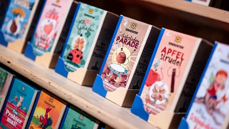 Reihe bunter Sonnentor Geschenkboxen auf Holzregal