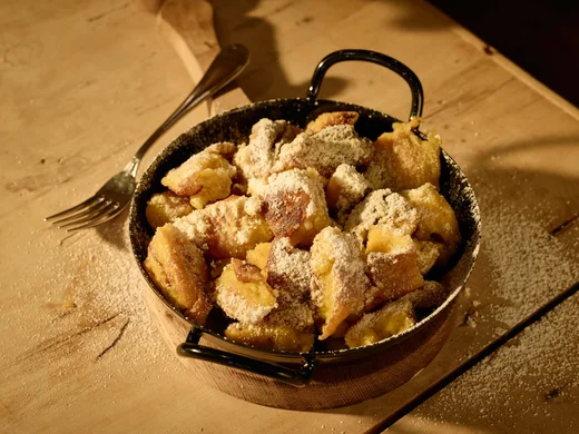 Kulinarik im Wiesenhof: Restaurant in Pertisau Kaiserschmarrn in einer Pfanne mit Puderzucker bestreut auf Holzuntergrund