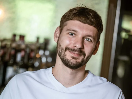 Arbeiten im Wiesenhof Mann wäscht Glas in Bar, trägt weißes Shirt mit Wiesenhof-Logo