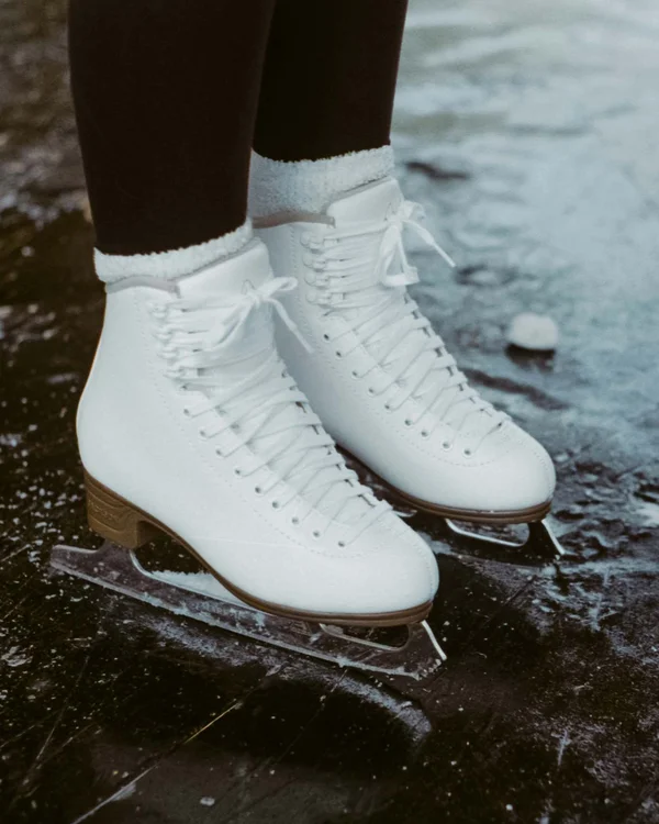 Wanderhotel Tirol: durchs Karwendel wandern und biken Weiße Schlittschuhe auf zugefrorenem See mit schwarzer Eiskleidung