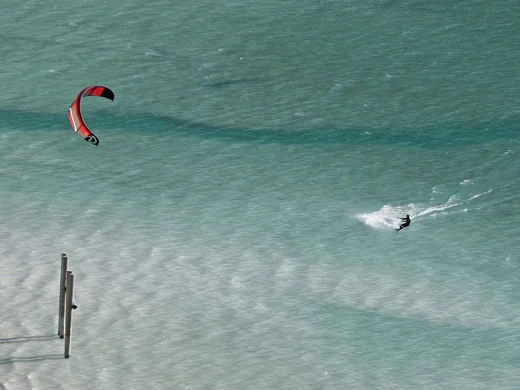 Ganz im Zeichen des Trainings: dieses Sporthotel am Achensee Kitesurfer mit rotem Kite auf blauem Wasser bei sonnigem Wetter
