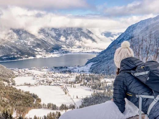 In, auf und rund um den Achensee Frau mit Rucksack blickt auf verschneites Tal und See in den Bergen