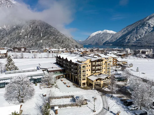 Ganz im Zeichen des Trainings: dieses Sporthotel am Achensee Winterliche Berglandschaft mit verschneitem Dorf und See unter blauem Himmel