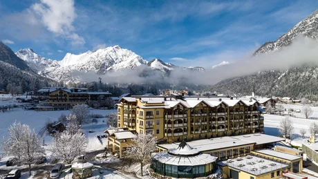 Hotelgebäude im verschneiten Bergtal mit Alpen und blauem Himmel