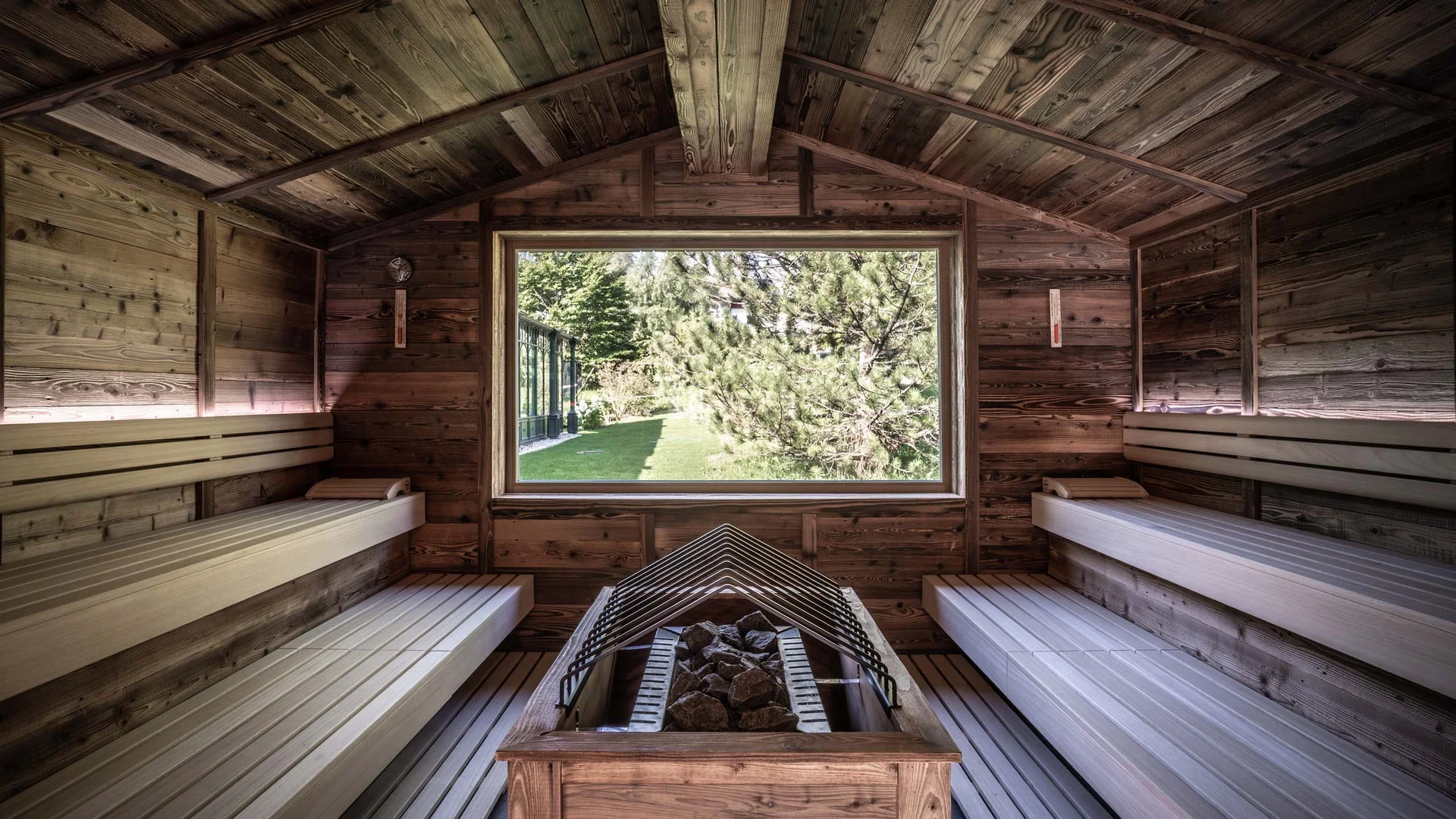 ENTspannen Innenraum einer Holzsauna mit großem Fenster und Blick auf grünen Garten