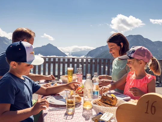 Euer Familienhotel am Achensee Familie beim Essen auf Terrasse mit Bergblick bei sonnigem Wetter