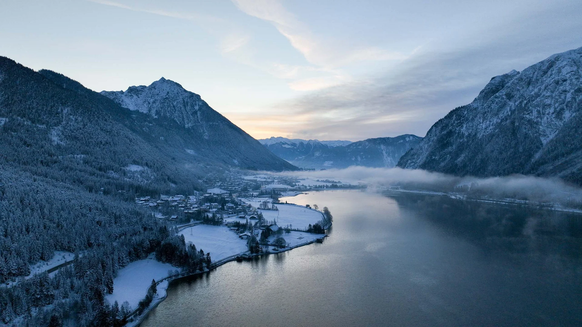 In, auf und rund um den Achensee Verschneites Tal mit Bergen und ruhigem See bei Dämmerung