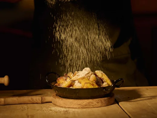 Auf in ein romantisches Hotel in Tirol Person bestreut Kuchen mit Puderzucker in einer dunklen Küche