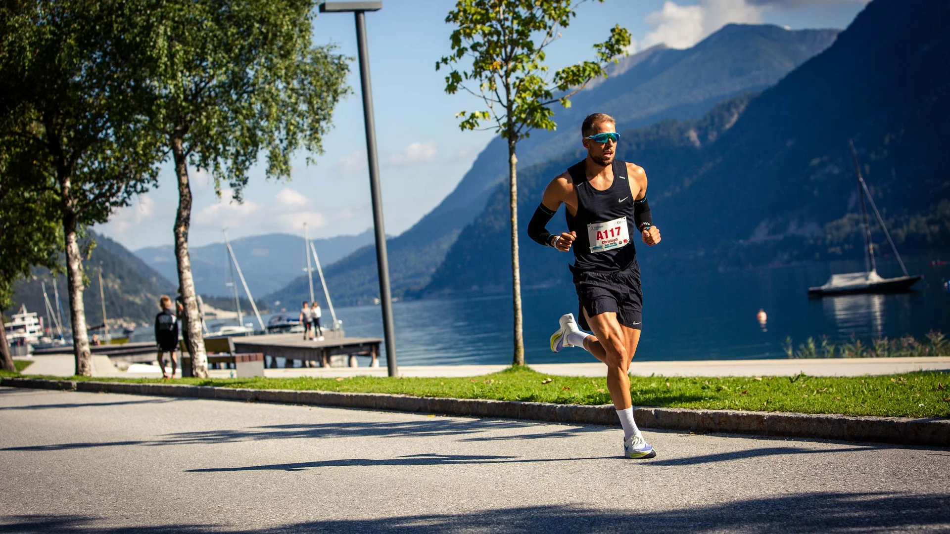 Mann läuft in einem Wettkampf am Seeufer mit Bergen im Hintergrund