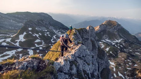 Zwei Kletterer sichern sich beim Bergsteigen auf einem schmalen Felsgrat im Gebirge