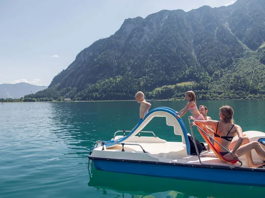 Euer Familienhotel am Achensee Familie auf Tretboot mit Rutsche auf Bergsee an sonnigem Tag