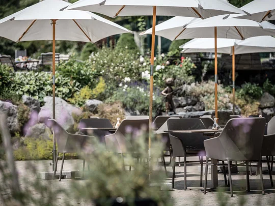 Der Wiesenhof in Pertisau und die Familie Entner mit Team Leere Terrasse mit weißen Sonnenschirmen und Stühlen im Garten