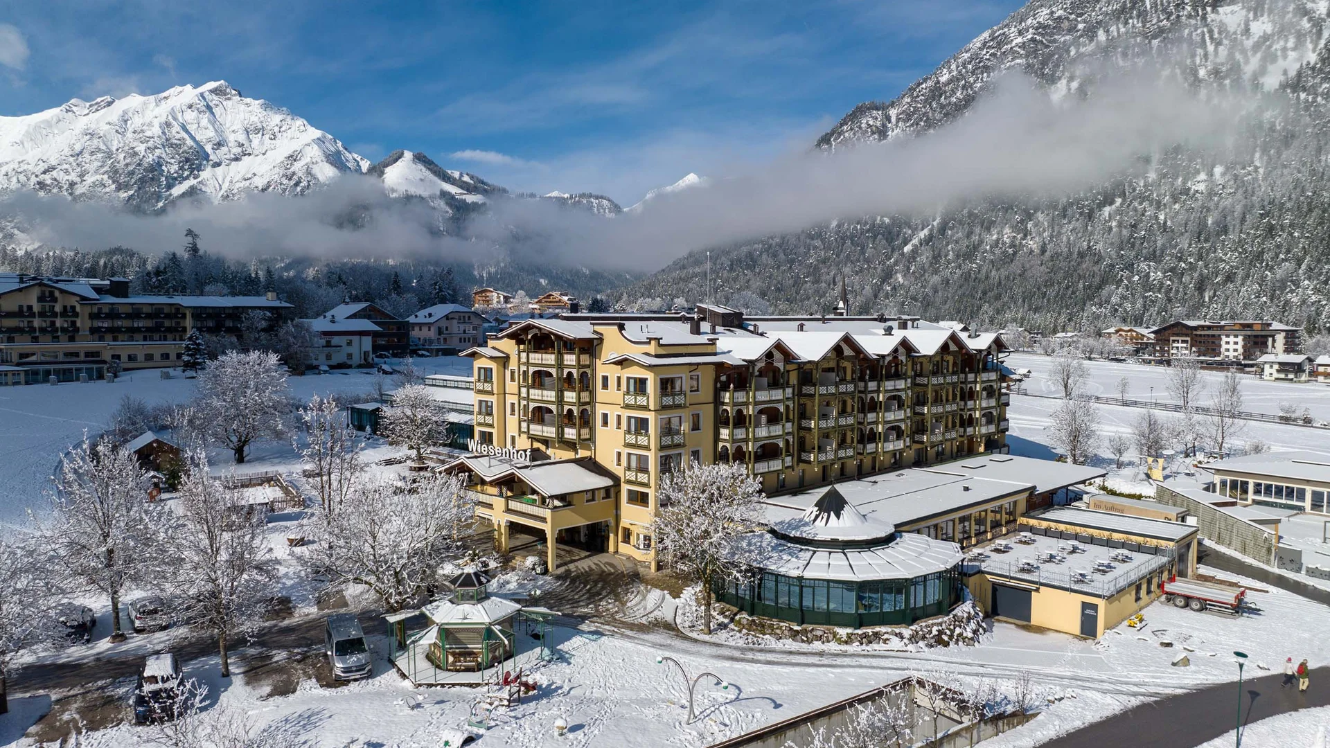 Schneebedecktes Hotel im Winter mit Alpen im Hintergrund und blauem Himmel