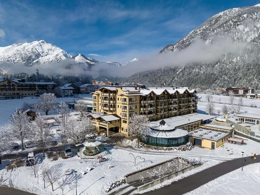 Schneebedecktes Hotel im Winter mit Alpen im Hintergrund und blauem Himmel