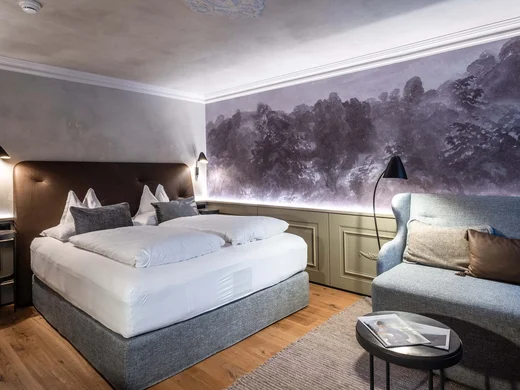 Gemütliches Hotelzimmer mit Doppelbett, Sofa und Wandkunst