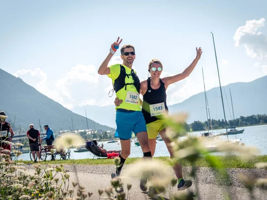 Zwei Läufer feiern glücklich während eines Laufs am See bei Sonnenschein