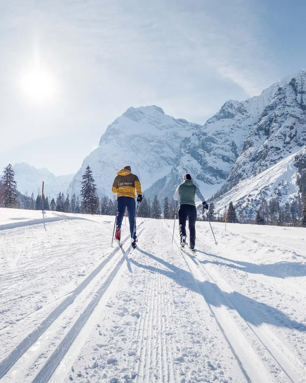 Wanderhotel Tirol: durchs Karwendel wandern und biken Zwei Skifahrer fahren auf verschneiter Berglandschaft bei sonnigem Wetter