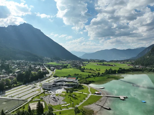 In, auf und rund um den Achensee Blick auf Bergdorf, grünes Tal, See und Wolken am Himmel