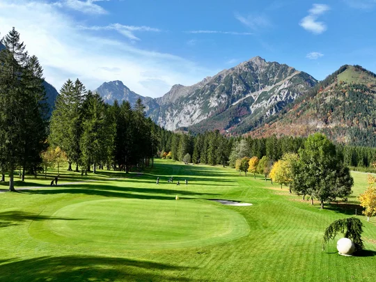Euer Golfhotel am Achensee Golfplatz vor Bergen mit grünen Bäumen und klarem blauem Himmel