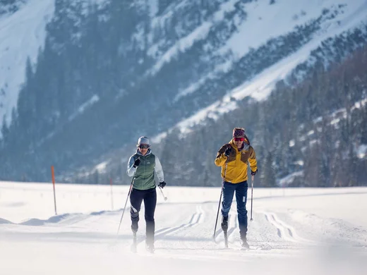 Ganz im Zeichen des Trainings: dieses Sporthotel am Achensee Zwei Langläufer im Winter bei sonnigem Wetter vor verschneiten Bergen