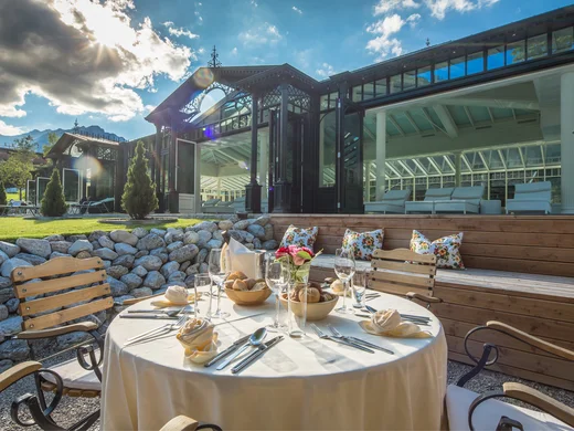 Kulinarik im Wiesenhof: Restaurant in Pertisau Gedeckter Außentisch mit Stühlen und Glasfassade im Hintergrund bei Sonnenschein