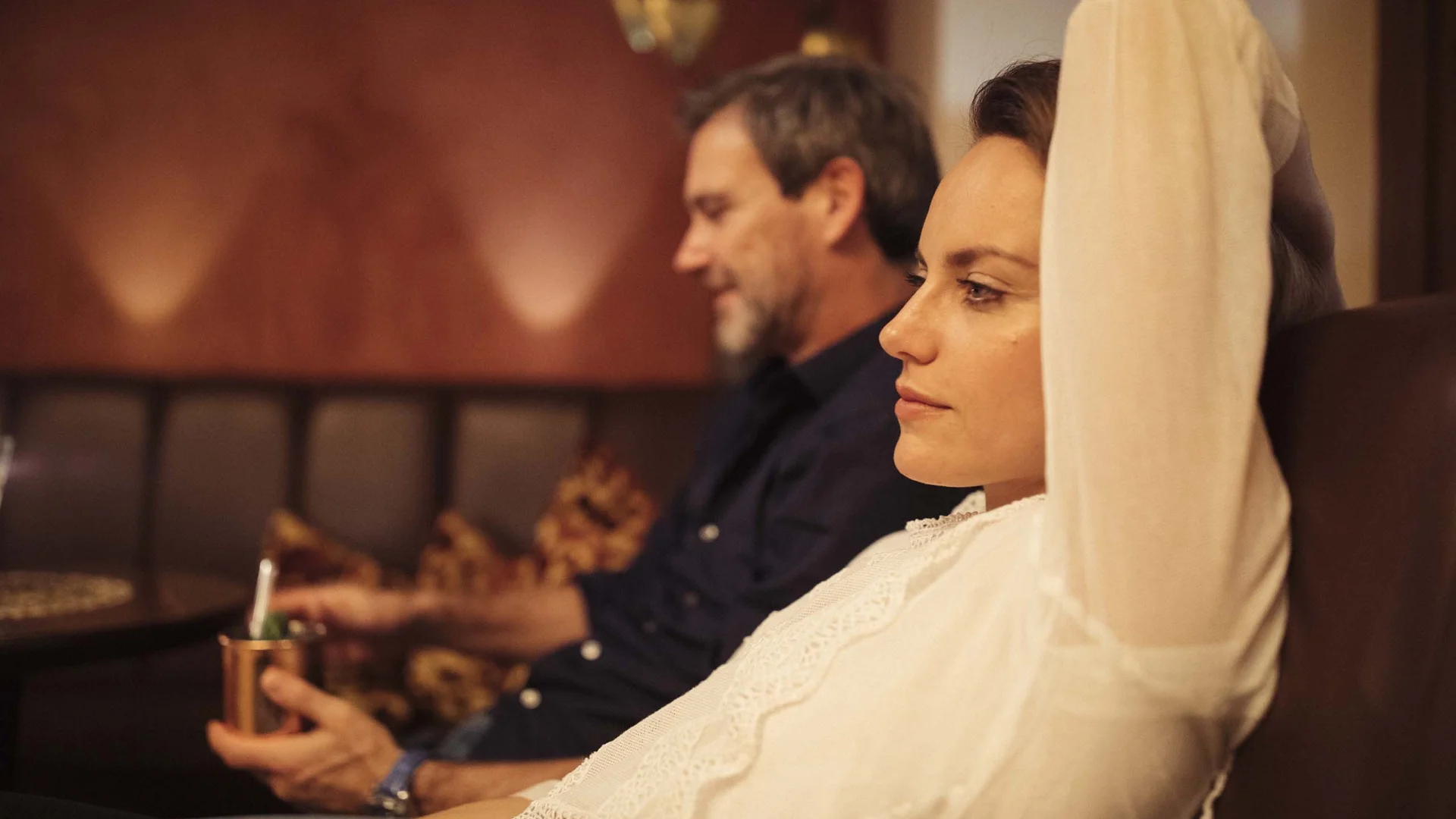 Auf in ein romantisches Hotel in Tirol Frau und Mann sitzen entspannt auf Sofa in gedämpftem Licht