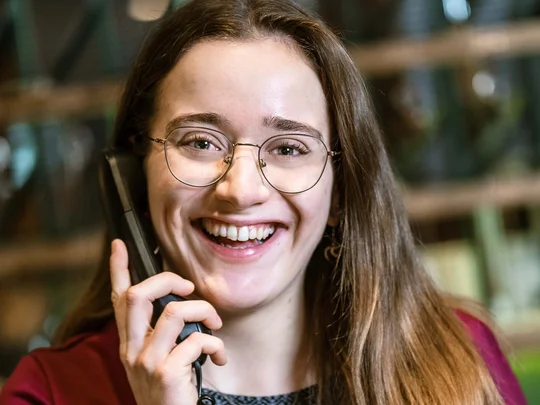 Arbeiten im Wiesenhof Lächelnde Frau mit Brille telefoniert am Arbeitsplatz