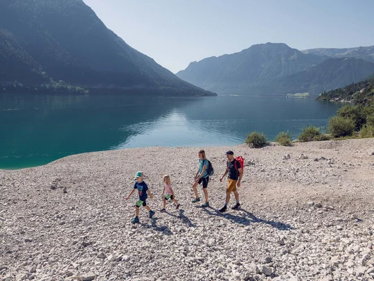 Euer Familienhotel am Achensee Familie wandert am Seeufer mit Bergen im Hintergrund