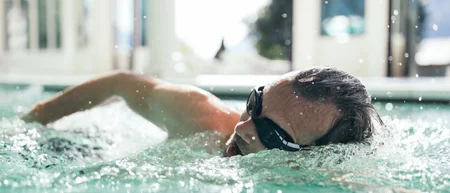 Mann schwimmt mit Schwimmbrille in einem Innenpool