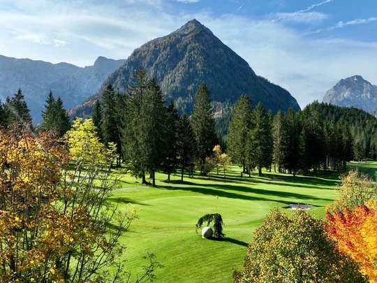 Euer Golfhotel am Achensee Berglandschaft mit Nadelbäumen und herbstlich gefärbten Laubbäumen vor blauem Himmel