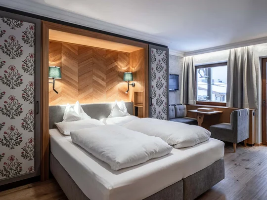 Zimmer und Suiten im Wiesenhof Gemütliches Hotelzimmer mit Doppelbett, Sitzecke und Balkon mit Bergblick