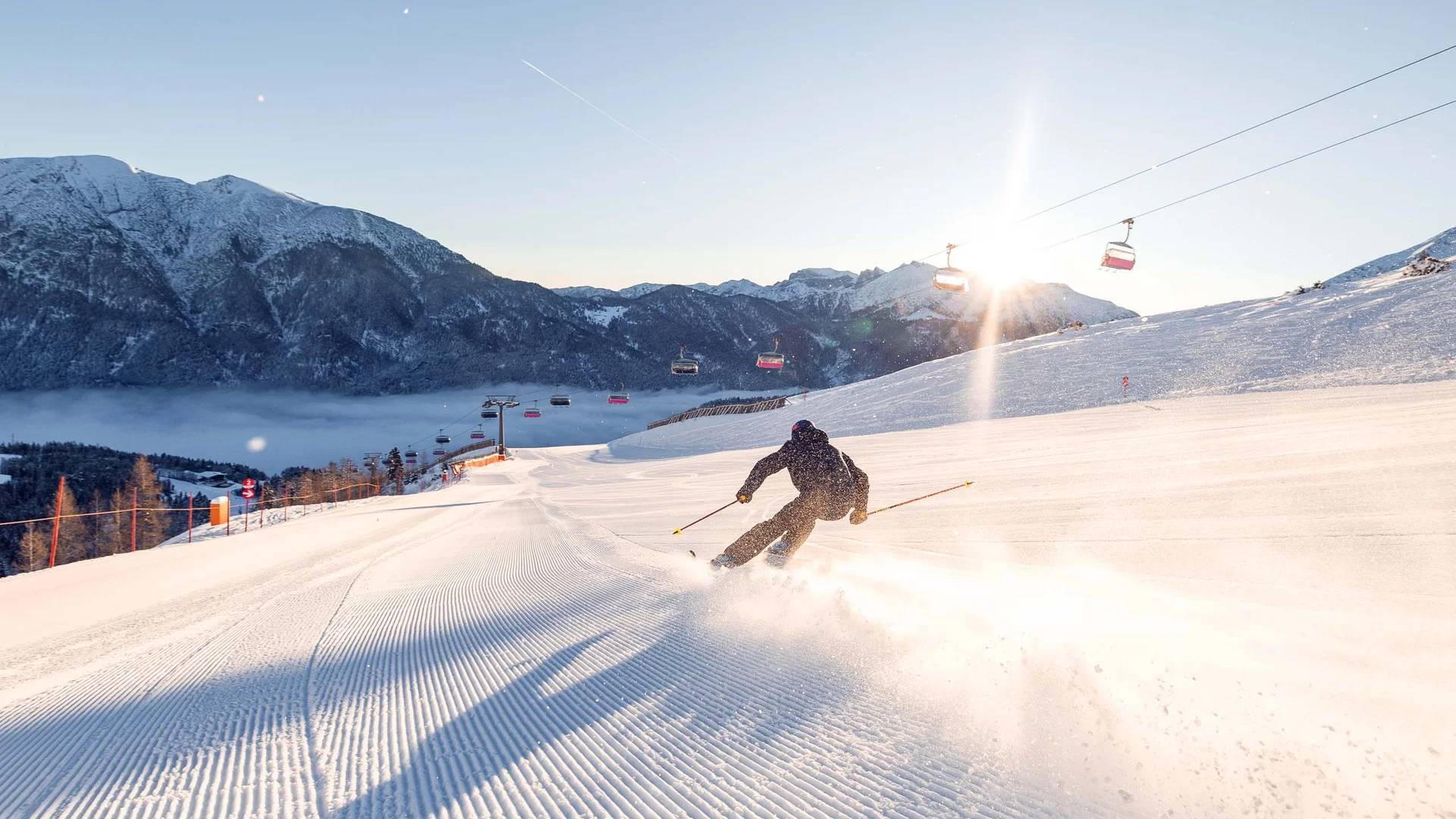 Ganz im Zeichen des Trainings: dieses Sporthotel am Achensee Skifahrer fährt auf frisch präparierter Piste bei Sonnenaufgang in den Bergen