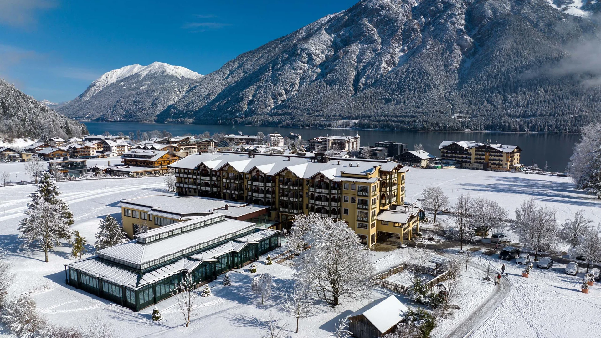 Der Wiesenhof in Pertisau und die Familie Entner mit Team Winterliche Alpenlandschaft mit schneebedecktem Dorf und See unter klarem blauem Himmel
