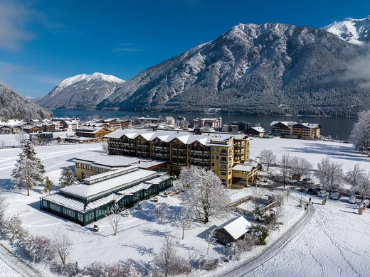 Winterliche Alpenlandschaft mit schneebedecktem Dorf und See unter klarem blauem Himmel