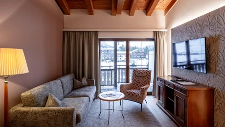 Gemütliches Wohnzimmer mit Sofa, Sessel, TV und Bergblick durch Fenstertür