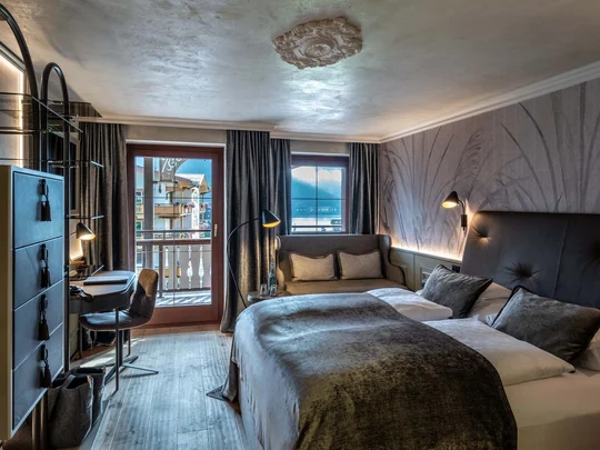 Zimmer und Suiten im Wiesenhof Modernes Hotelzimmer mit Doppelbett, Sofa und Blick auf Balkon und Berge