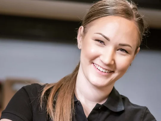 Arbeiten im Wiesenhof Lächelnde Frau presst Orangen mit Presse vor Karaffen mit Saft