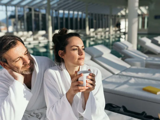 Das 4-Sterne-Hotel am Achensee: der Wiesenhof Paar in Bademänteln entspannt am Pool mit Tasse und Liegestühlen