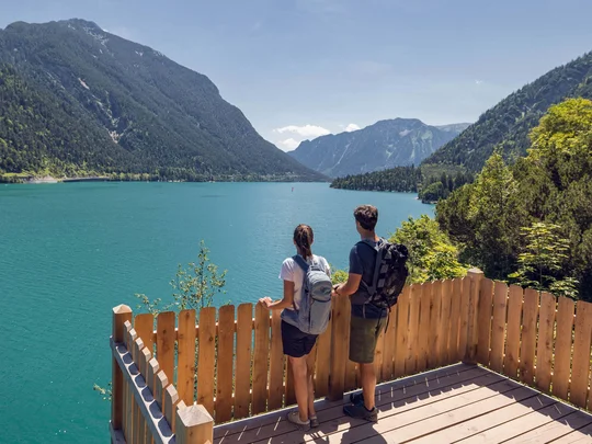 Sehenswürdigkeiten am Achensee rund um den Wiesenhof Zwei Wanderer genießen den Ausblick auf einen Bergsee und bewaldete Berge