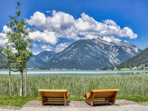 In, auf und rund um den Achensee Zwei Holzbänke mit Blick auf See, Berge und blauen Himmel mit Wolken